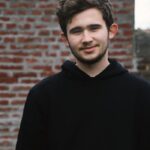 Smiling young man standing on street near brick wall